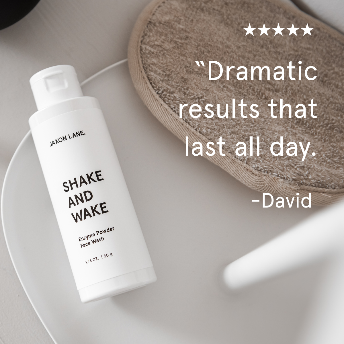 Jaxon Lane Shake and Wake Enzyme Powder Face Wash bottle on a white surface with a brown textured disc and white text.