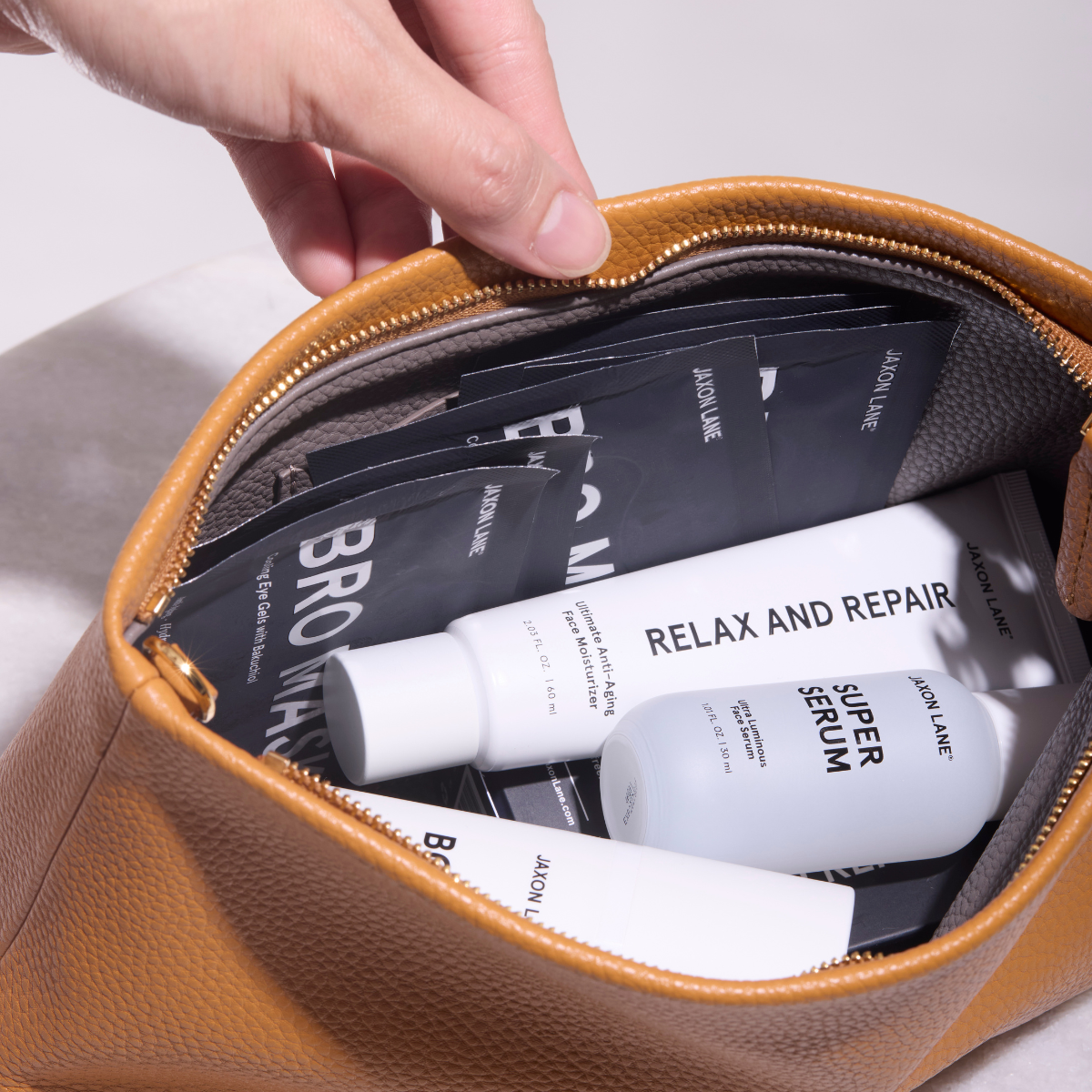 Handbag with skincare products including 'Super Serum' and 'Relax and Repair' on a neutral background